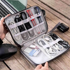Organized electronic accessories in a travel case on a wooden surface with a laptop and mouse.