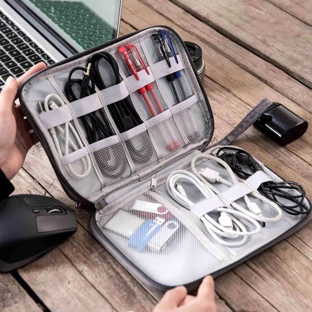Organized electronic accessories in a travel case on a wooden surface with a laptop and mouse.